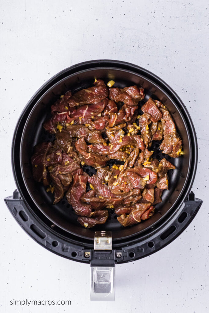 Marinated beef added to the air fryer basket. 