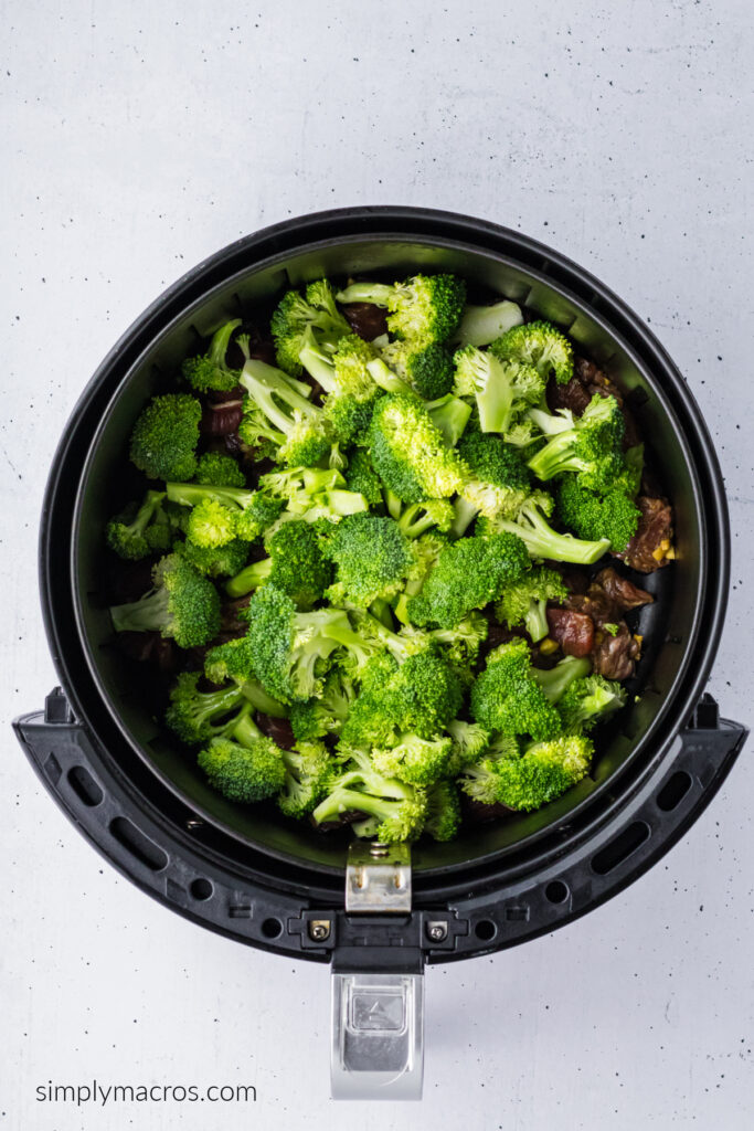 Beef and broccoli in the air fryer basket, ready to be cooked. 