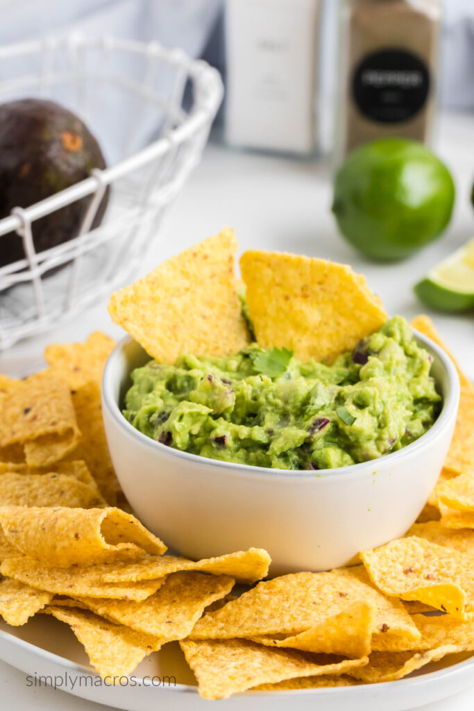 Homemade guacamole in a white bowl surrounded by tortilla chips. 