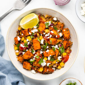 Overhead photo of a quinoa sweet potato bowl, topped with a lemon, ready to serve.