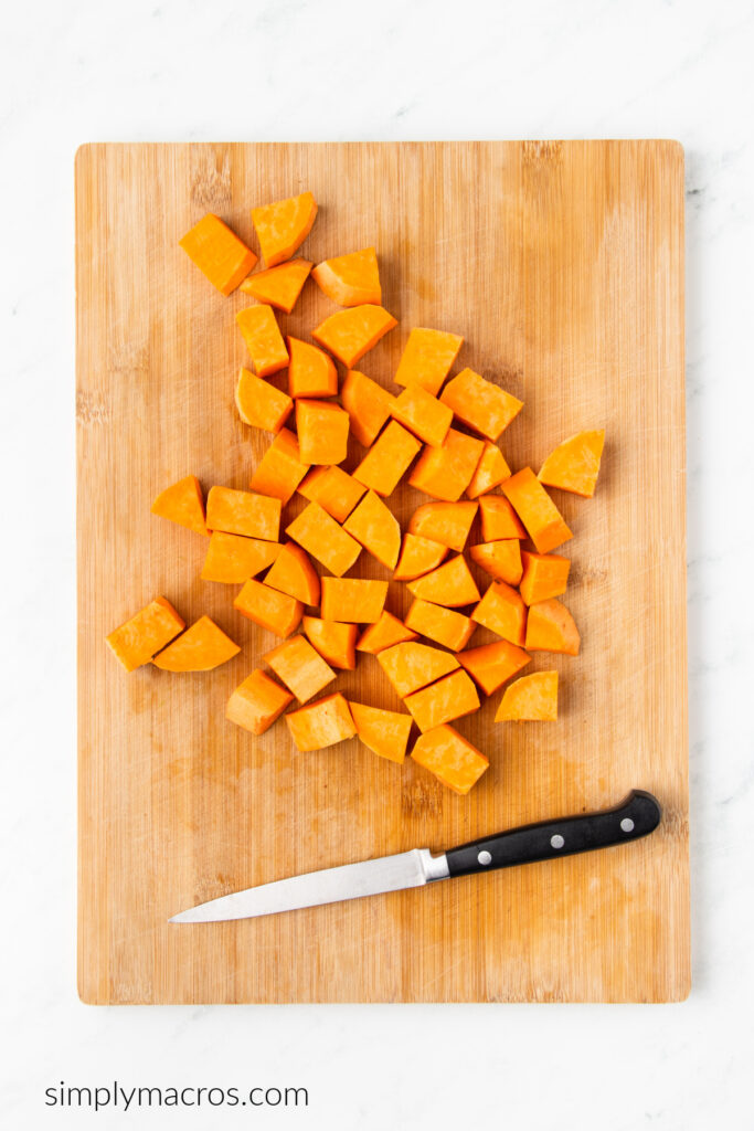 Sweet potatoes diced on a wooden board, ready to toss with oil and bake to soften. 