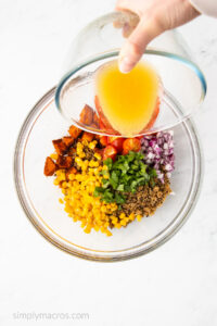 Veggies in a bowl being combined with the sauce.