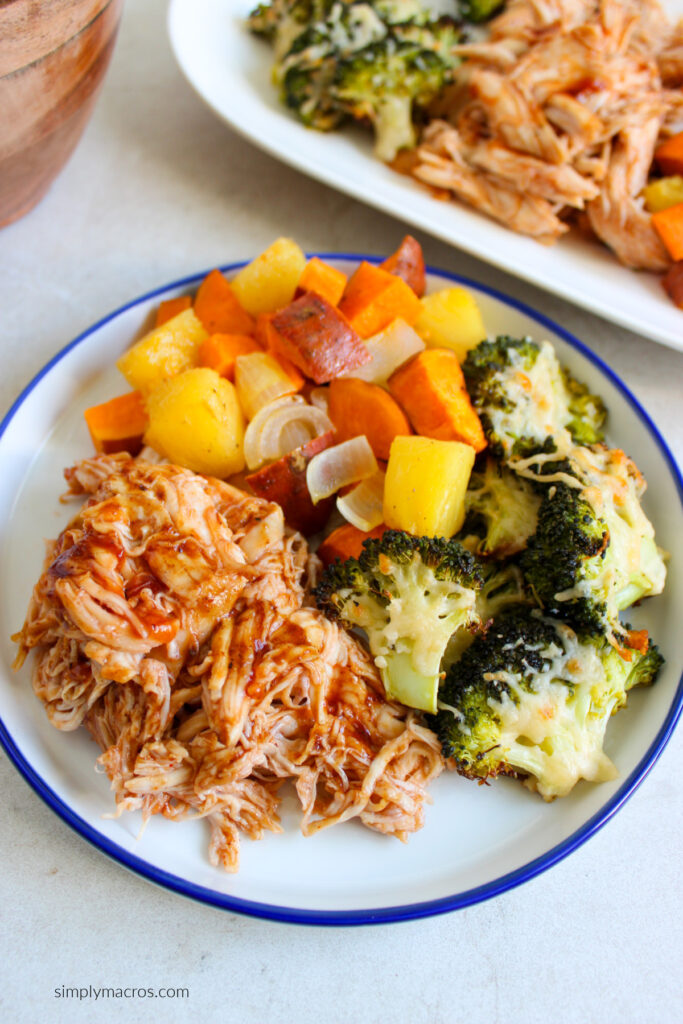 Shredded bbq chicken on a plate with broccoli and a mixture of veggies, ready to serve. 