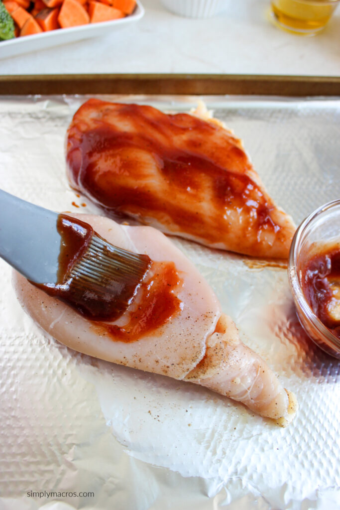 chicken being brushed with BBQ sauce.