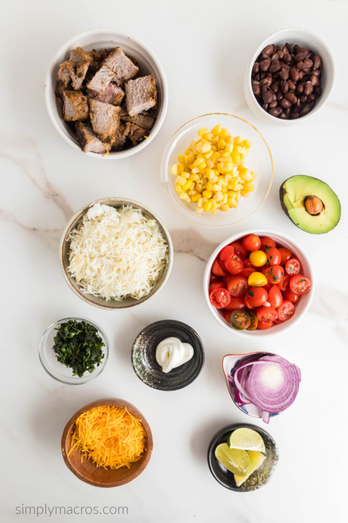 Ingredients for a steak burrito bowl recipe, all seperated in bowls to be put together. 