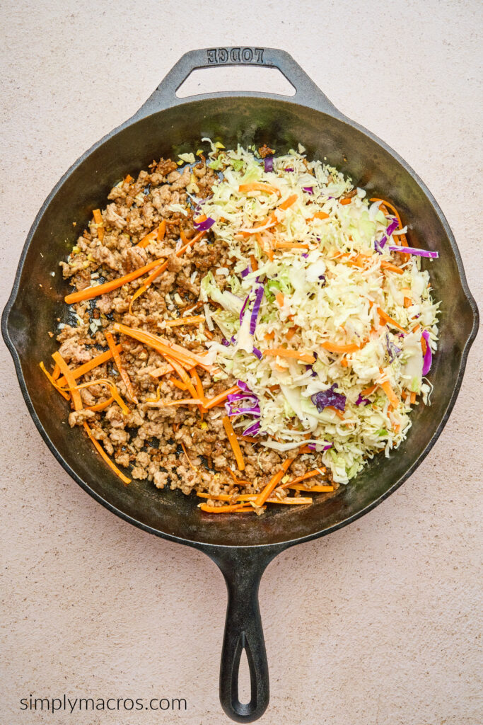 Ground beef, carrot matchsticks, and coleslaw mix in a skillet, ready to cook. 