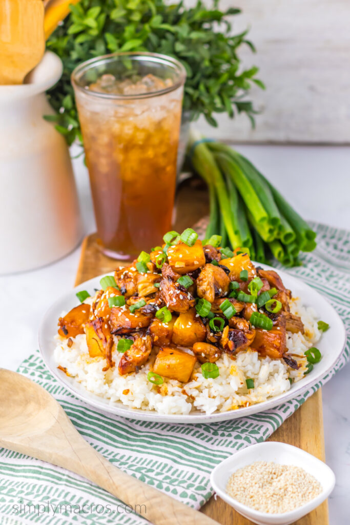 Brown sugar pineapple chicken over a bed of rice with scallions and sesame seeds, ready to eat. 