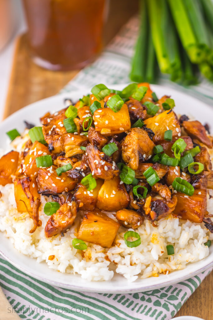 Brown sugar pineapple chicken over a bed of rice with chopped scallions and sesame seeds. 