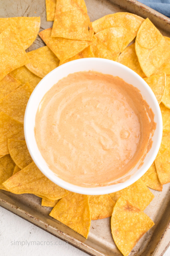 High protein cottage cheese queso in a white bowl surrounded by homemade tortilla chips.