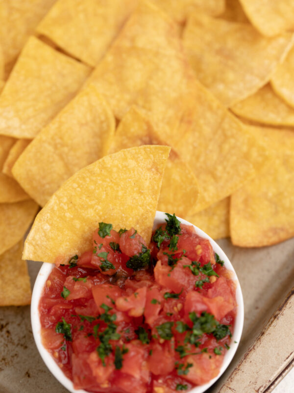 Homemade tortilla chips on a tray with a side of salsa.