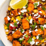 Close up of a quinoa sweet potato bowl with a lemon wedge.