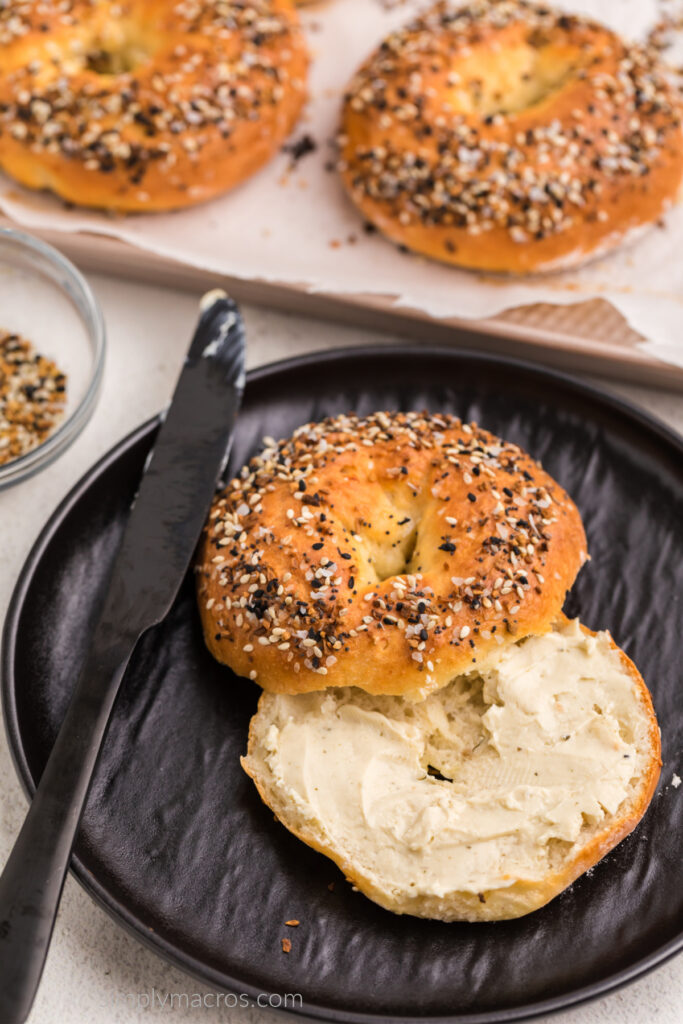 Cottage cheese bagel topped with everything bagel seasoning, sliced, and one side topped with cream cheese. 