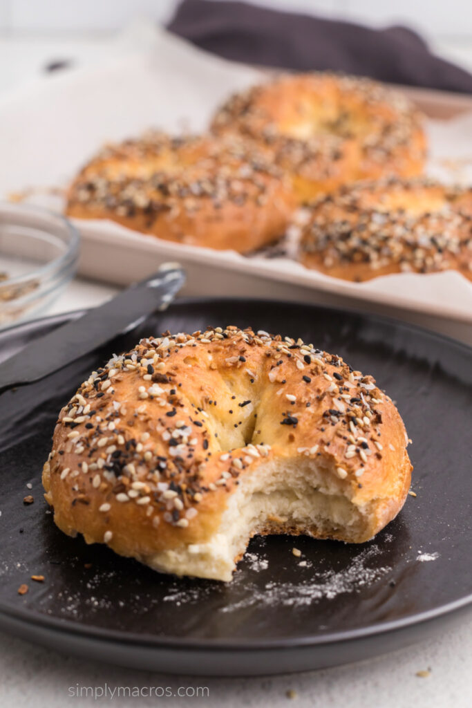 Cottage cheese bagel on a black plate with a bite missing. 