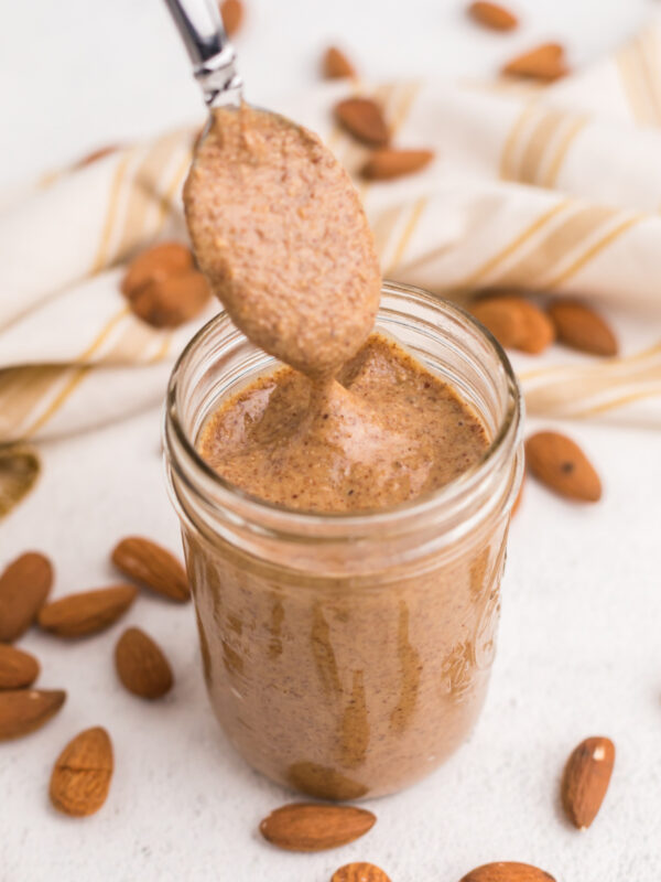 Creamy homemade almond butter being spooned from a jar.