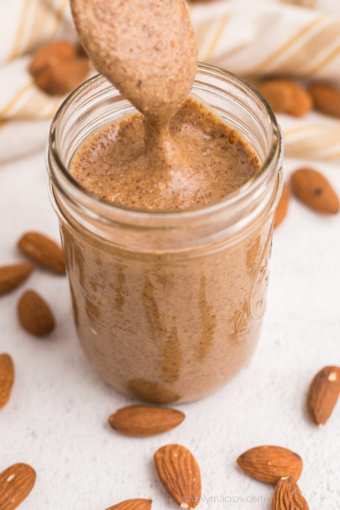 Close up of homemade almond butter in a jar with a spoon. 