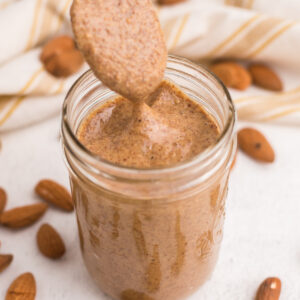 almond butter being scooped from a jar with a spoon.