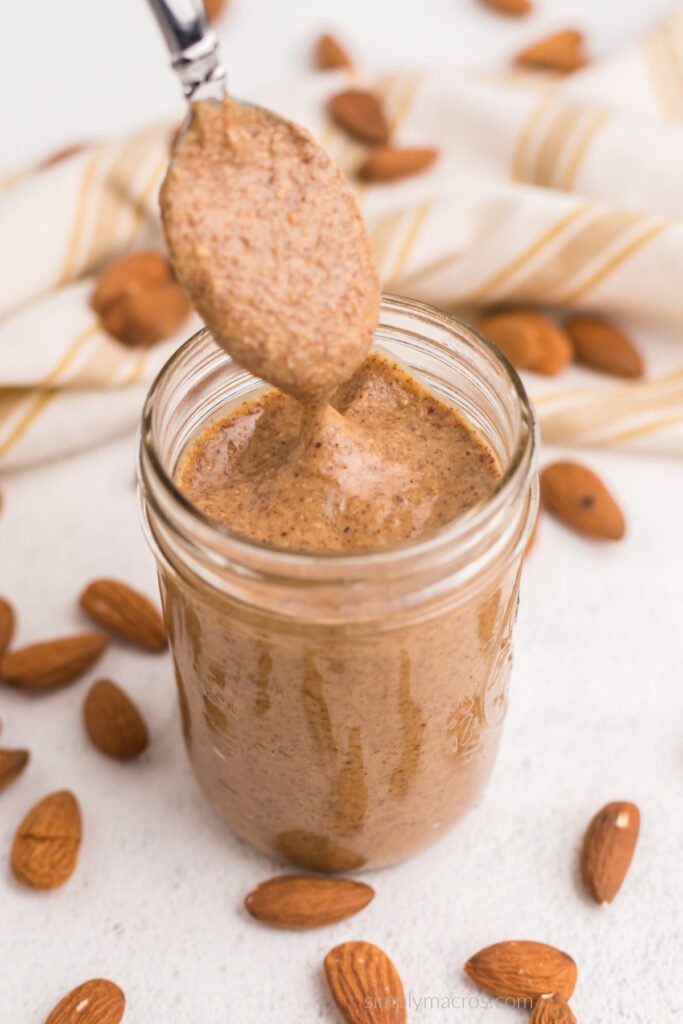 Spoon of almond butter in the jar of almond butter, ready to serve. 