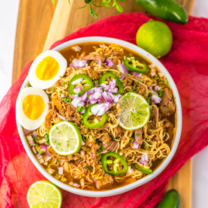 Birria ramen recipe with egg and sliced limes on top. Ready to eat.