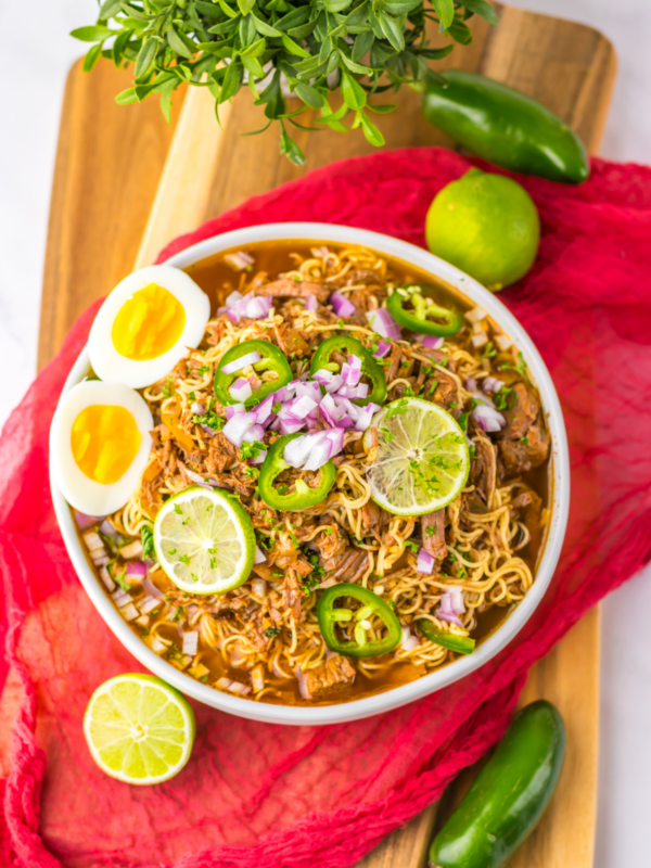 Birria ramen recipe with egg and sliced limes on top. Ready to eat.