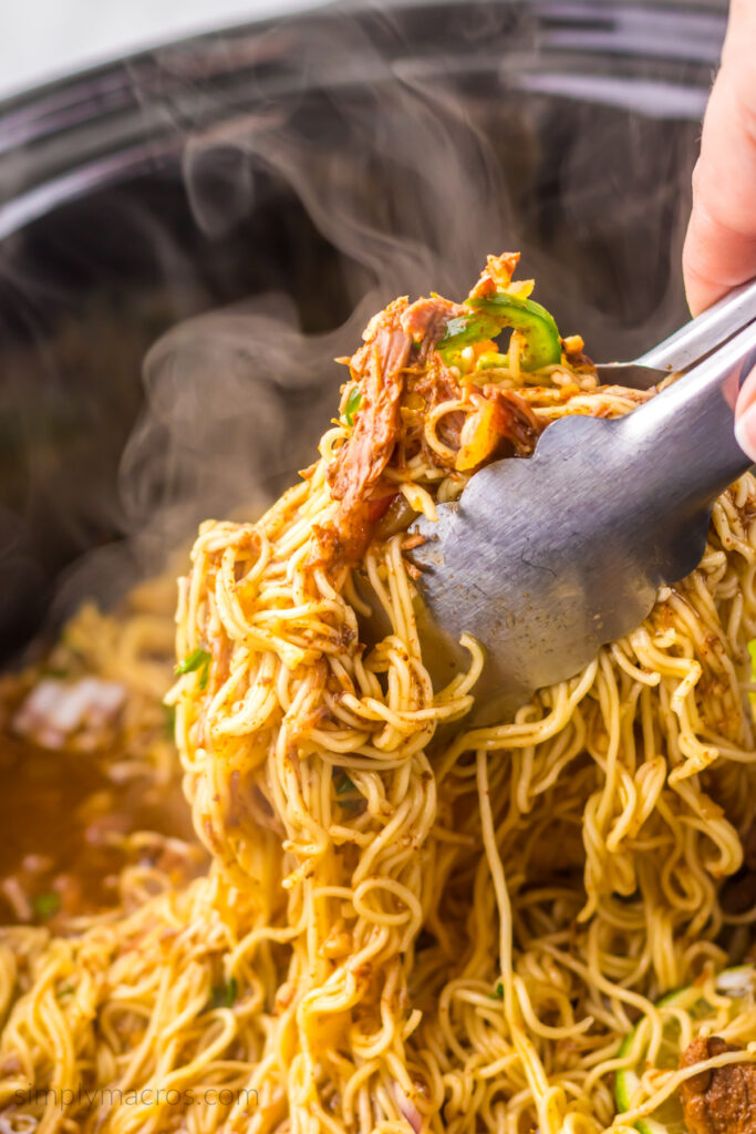 Scooping the Barria ramen recipe from the slow cooker into bowls before serving. 