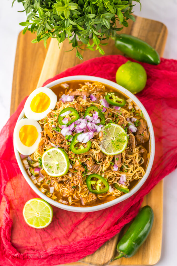 Birria Ramen bowl with diced onion, jalapenos, eggs, and limes for garnish. Ready to serve. 