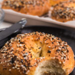 Close up photo of a cottage cheese bagel on a plate with a bite missing, pinnable image.