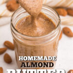 Homemade Almond butter in a jar with a spoon scooping some out. Pinnable image.