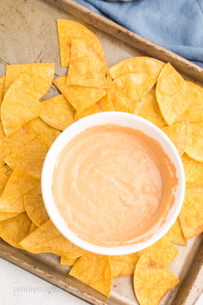 Homemade tortilla chips surrounding a bowl of high protein cottage cheese queso. 