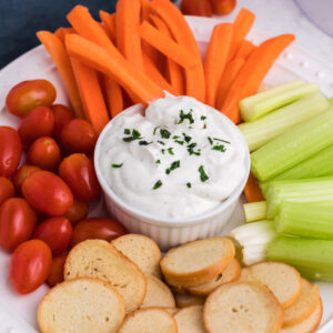 Cottage cheese ranch dip surrounded by vegetables on a white plate.