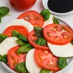 Easy caprese salad layerd with sliced mozzarella and heirloom tomatoes, topped with fresh basil.