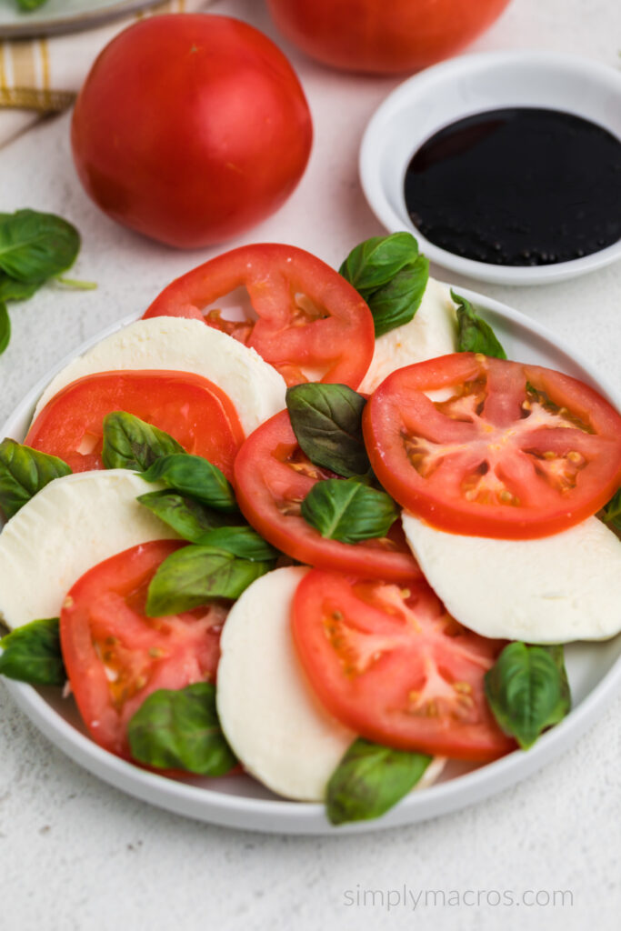 Caprese salad on a white plate with a bowl of balsamic glaze. Ready to eat. 