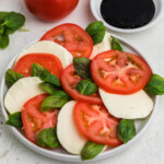 Caprese salad recipe topped with fresh basil and made with sliced heirloom tomatoes and sliced mozzarella.