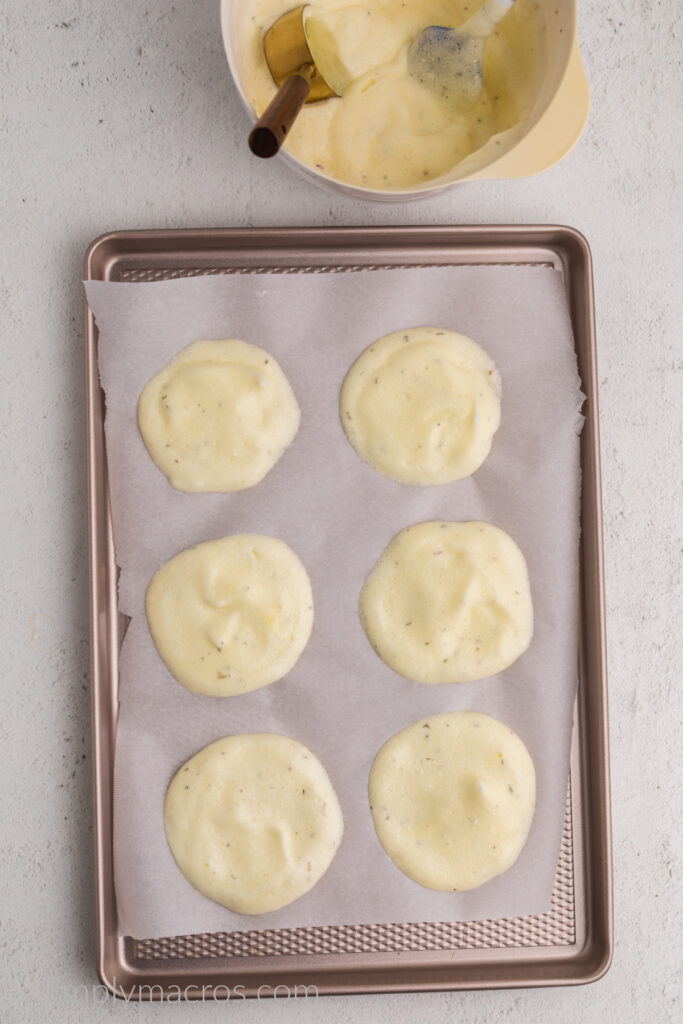 Baking sheet lined with parchmnet paper with cloud bread mixture scooped on top, ready to bake. 