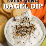 CLOSE UP OF BAGEL CHIP BEING DIPPED into the everything bagel chip. Pinnable image.