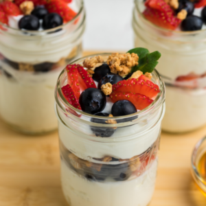 Greek yogurt parfait topped with granola and fresh fruit in a jar, ready to eat.