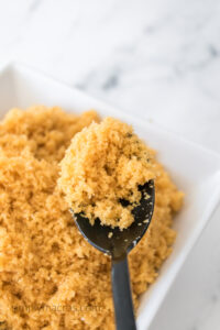 Brown sugar being scooped out of a bowl with a spoon.