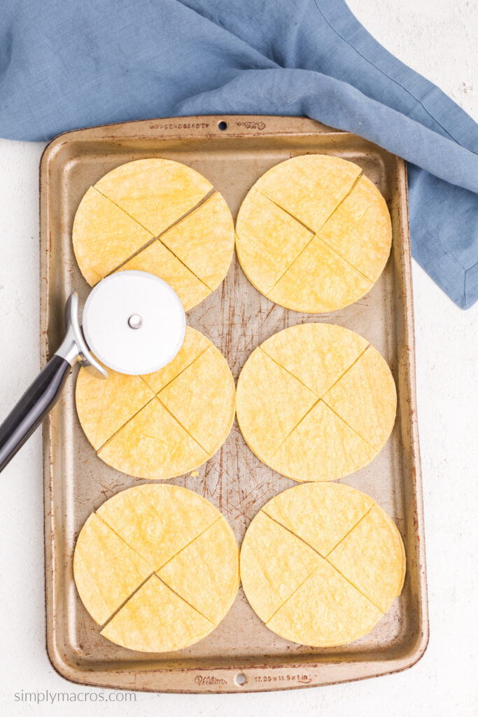 Tortillas on a tray that have been brushed with oil and cut into quarters.