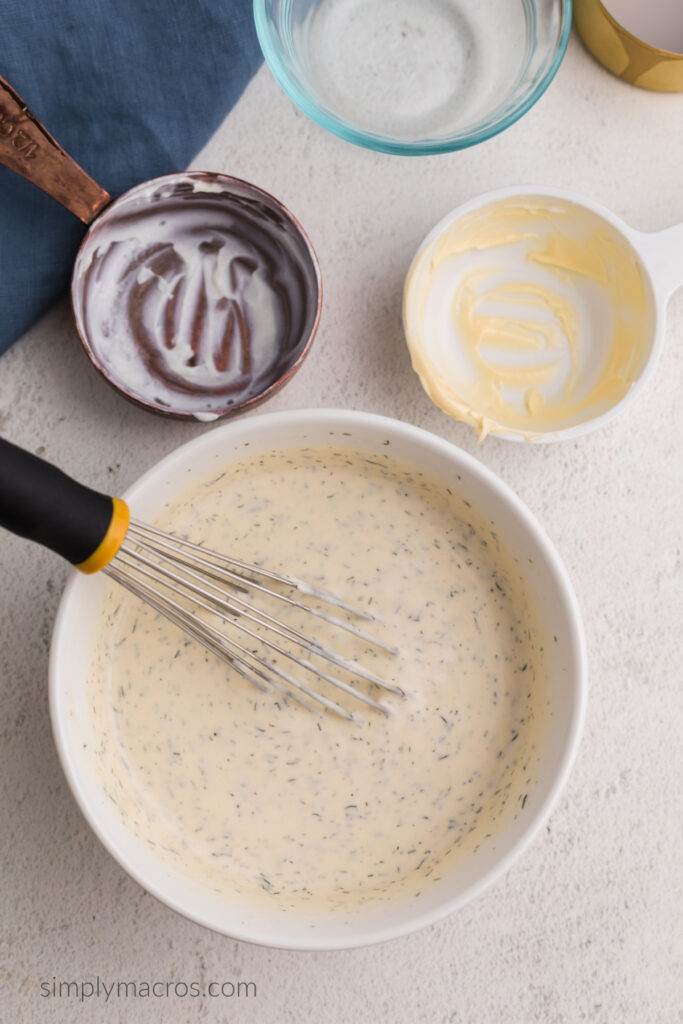 Bowl with whisked low calorie ranch dressing, ready to be transferred to a jar to be refrigerated before serving.