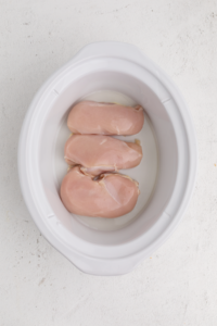 chicken layered in the bottom of the slow cooker