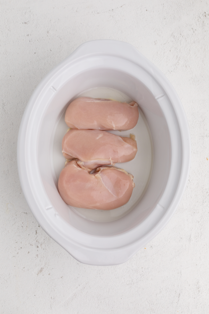 Chicken breasts placed into the bottom of the slow cooker. 