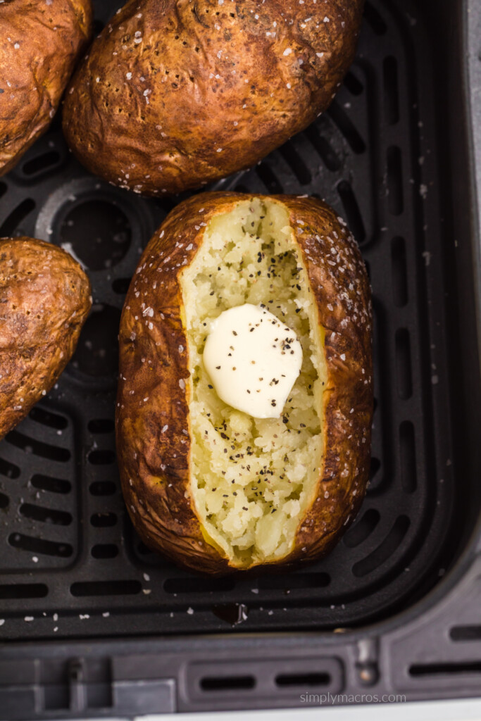 Cooked baked potato in air fryer basket.