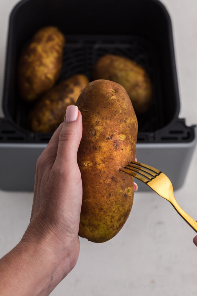 Russet potato being pierced with a fork before air frying.