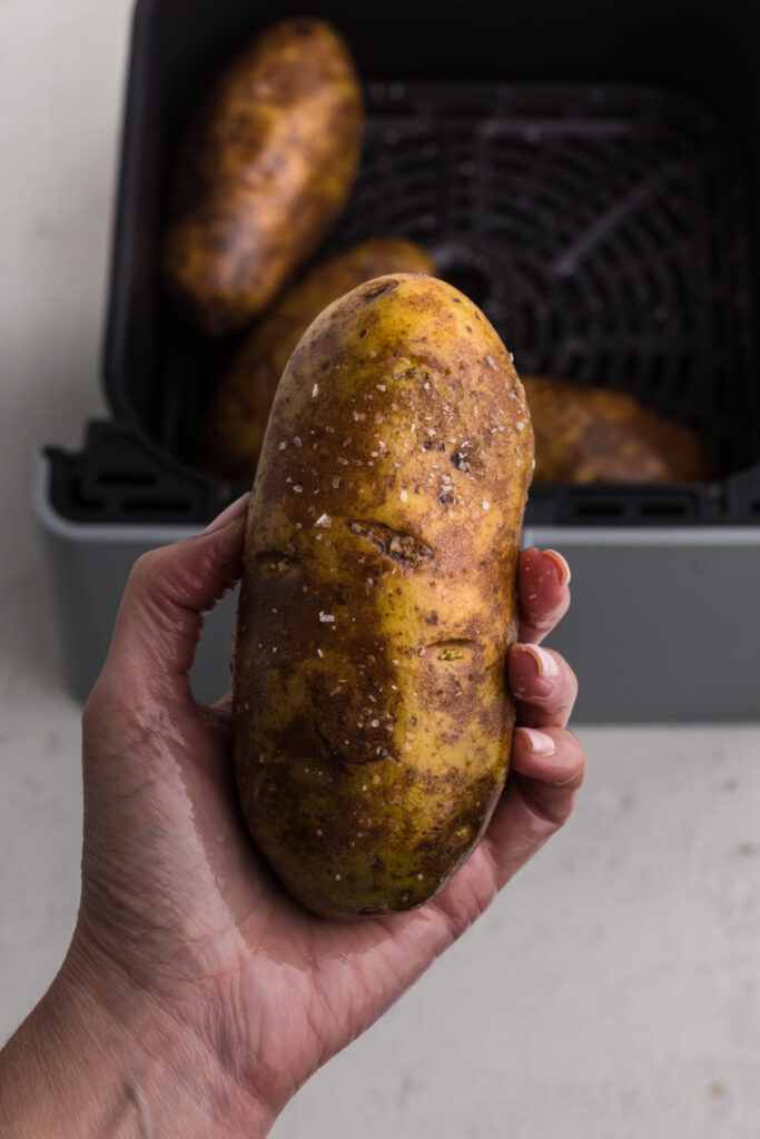 Hanf holding a potato thats been covered in olive oil and kosher salt. 