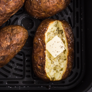 Close up of baked potato in air fryer basket.