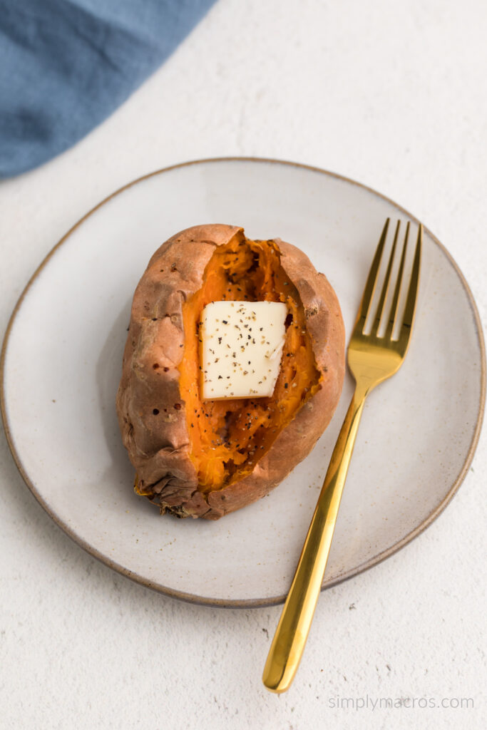 Air fried sweet potato on a plate with butter and seasoning. 