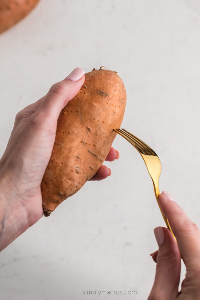 sweet potato being poked with holes with a fork before air frying. 