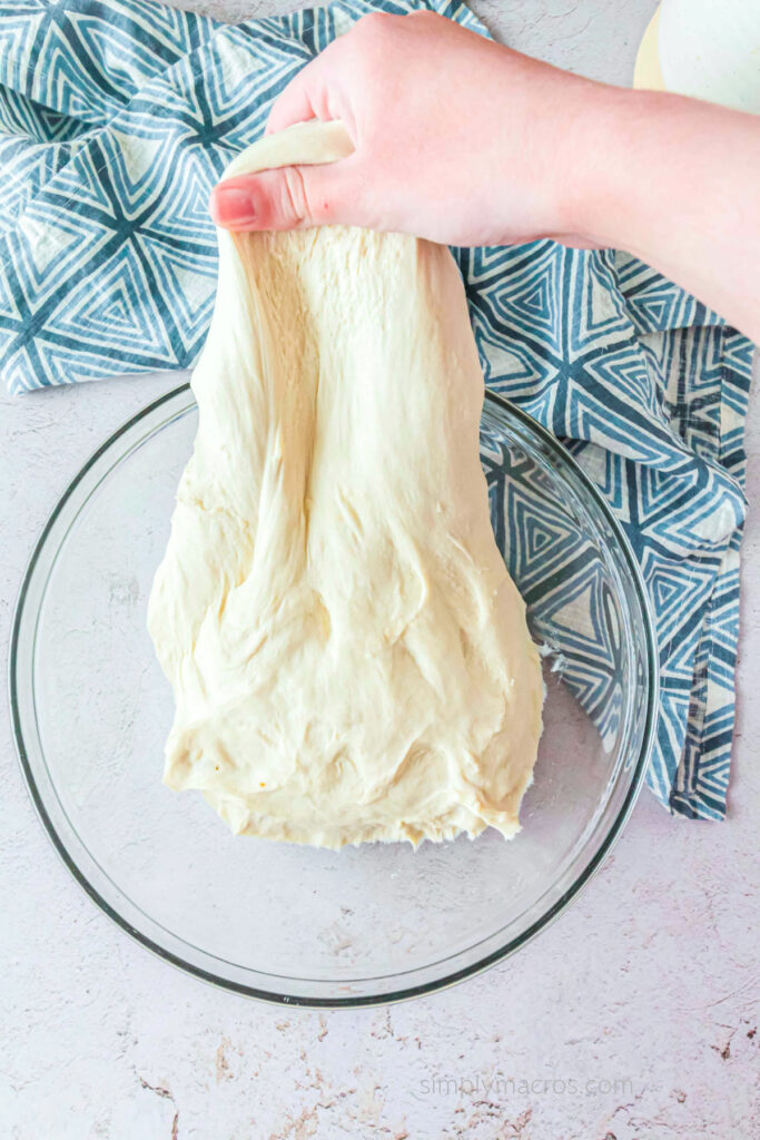 Stretching the dough with a hand before covering and allowing it to rest. 