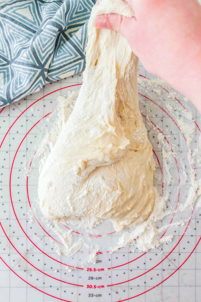 Dough on a floured work surface being stretched. 