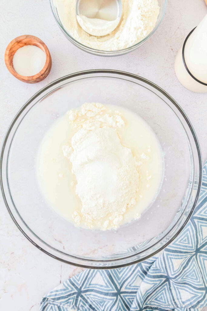 Half of the dough added to the started in a bowl, ready to mix. 