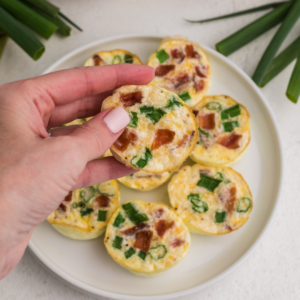 Egg white bites on a plate and a hand holding one to eat.